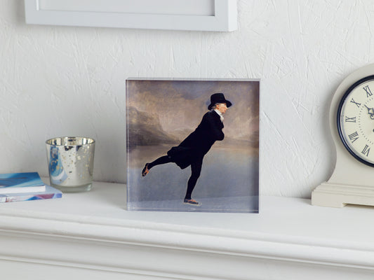 Framed artwork of a person in a dark outfit on a white surface with a clock and candle in the background.