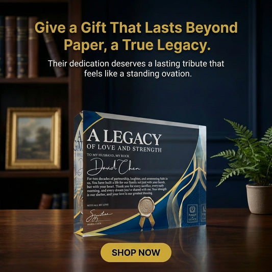Glass award with engraved text on a wooden surface, surrounded by books and a plant.
