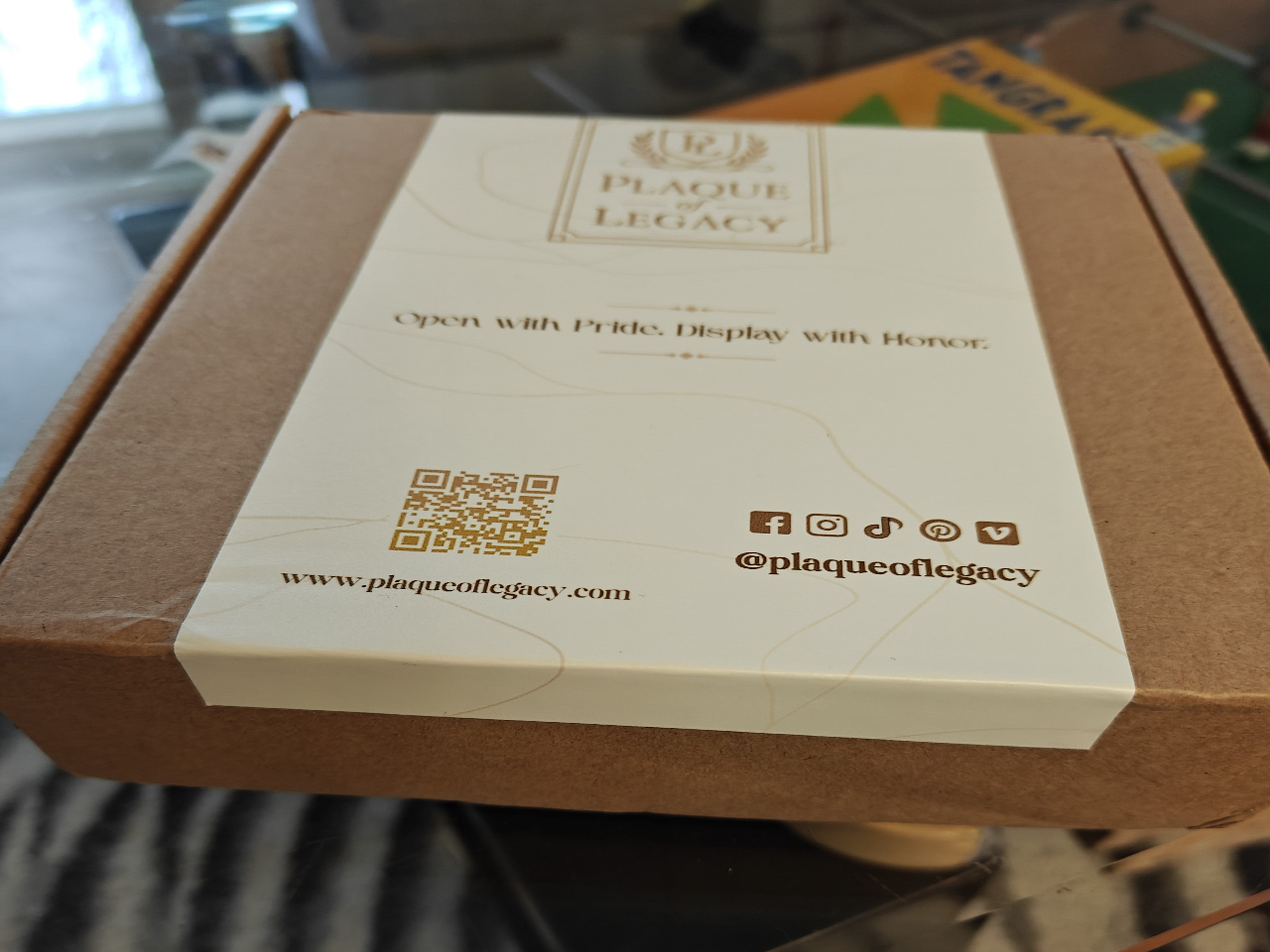 Product packaging with 'Plaque Legacy' branding and QR code on a cardboard box.