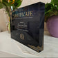 Acrylic certificate holder with gold text on a white surface with plants in the background